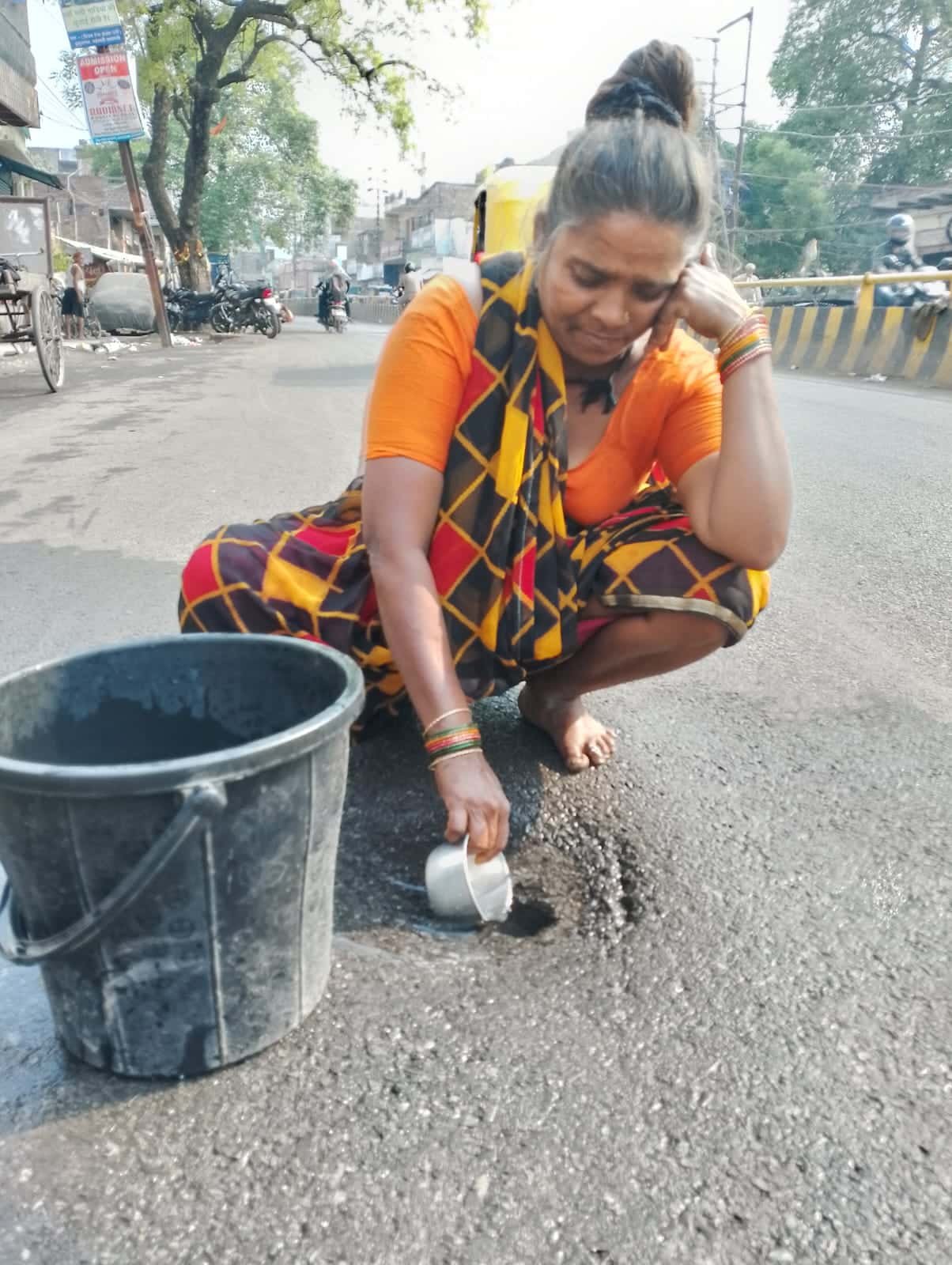 बनारस में सड़क से रिस रहे पानी से प्यास बुझा रहे बासफोर समुदाय के लोग